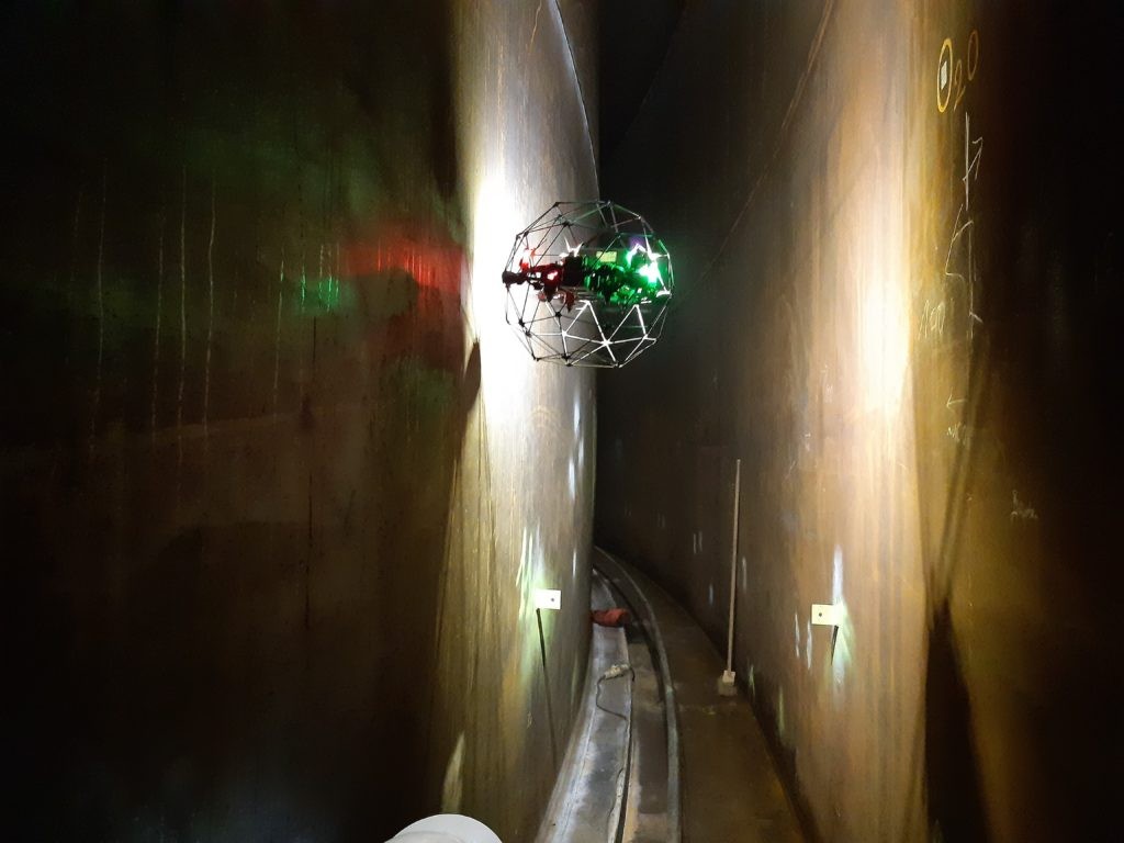 Caged Elios drone inside a dark tank